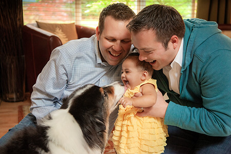 Two same-sex adoptive parents with an adopted child play